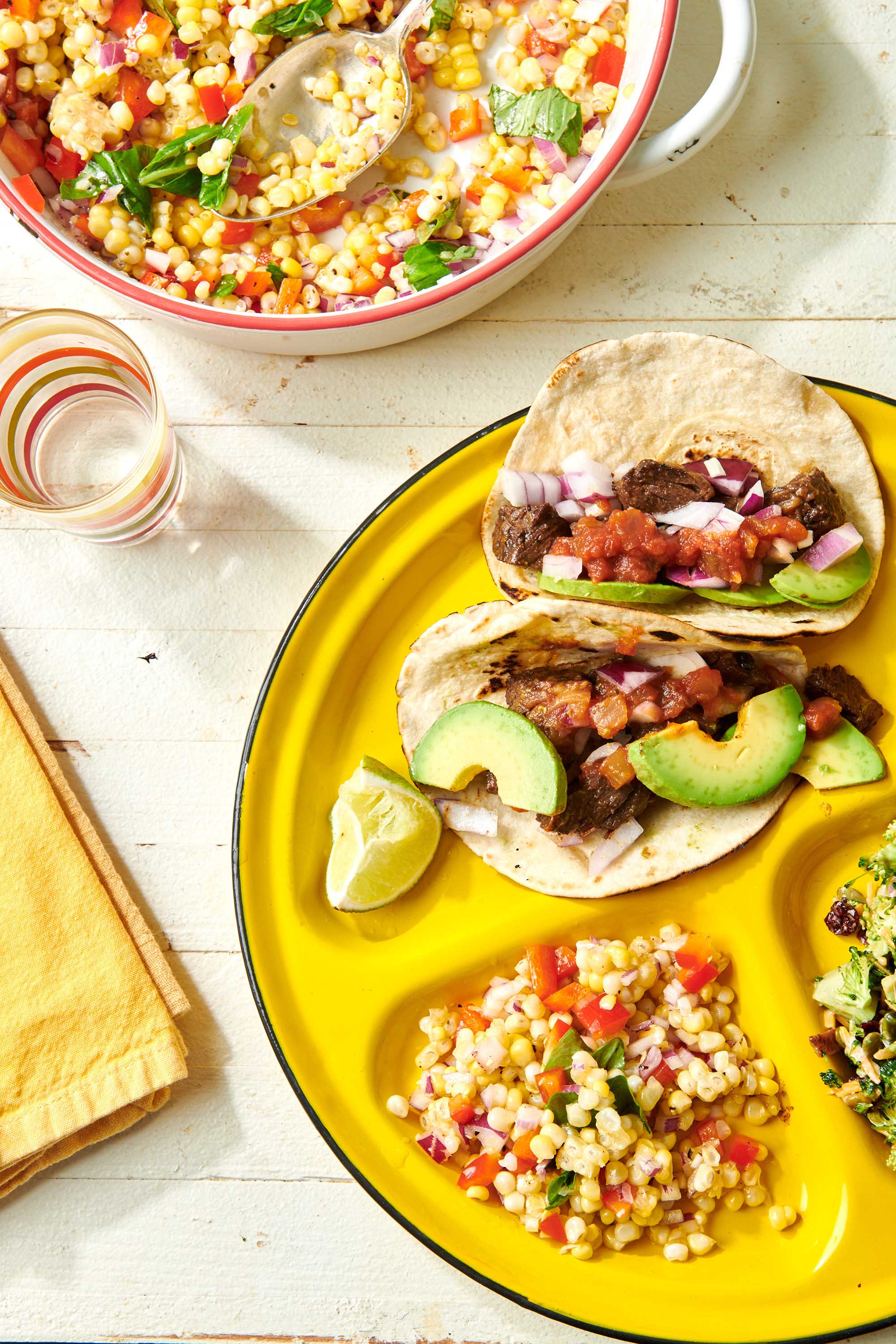 Steak Street Tacos on a yellow plate with corn salad.