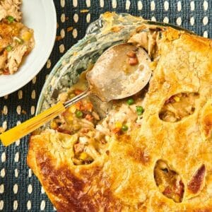 Spoon with turkey pot pie on table with plates.