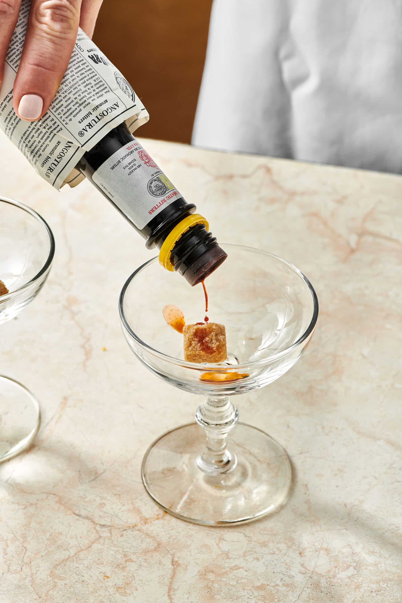 Bitters being poured into a long-stemmed glass.