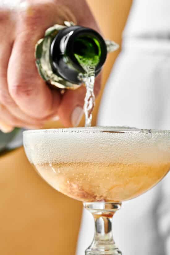 Champagne filling a long-stemmed glass for a French 75.