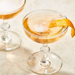 Long-stemmed glass of French 75 topped with orange peel.