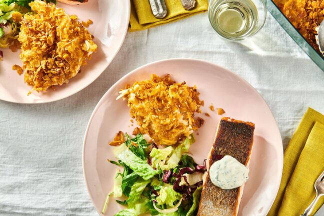 Pink plate set with Funeral Potatoes, salmon, and salad.