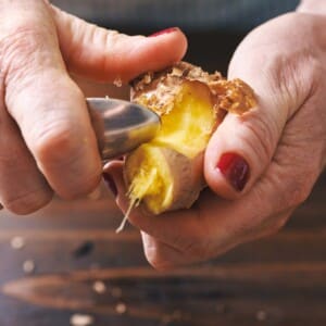 Woman peeling ginger with spoon.