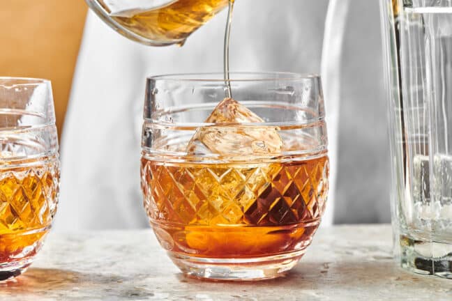 Old Fashioned pouring over ice in a rocks glass.