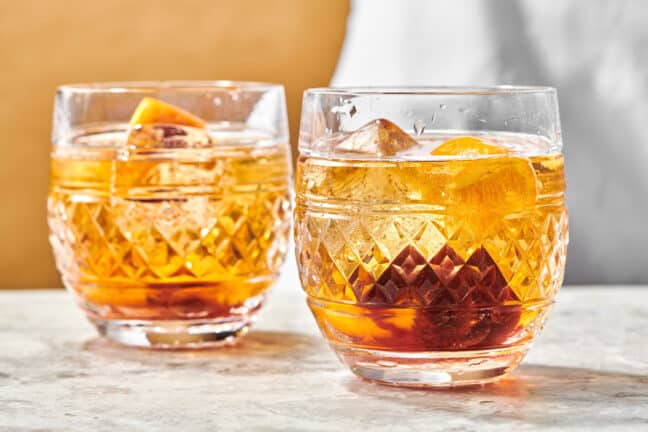 Old Fashioneds in rock glasses on a marble surface.