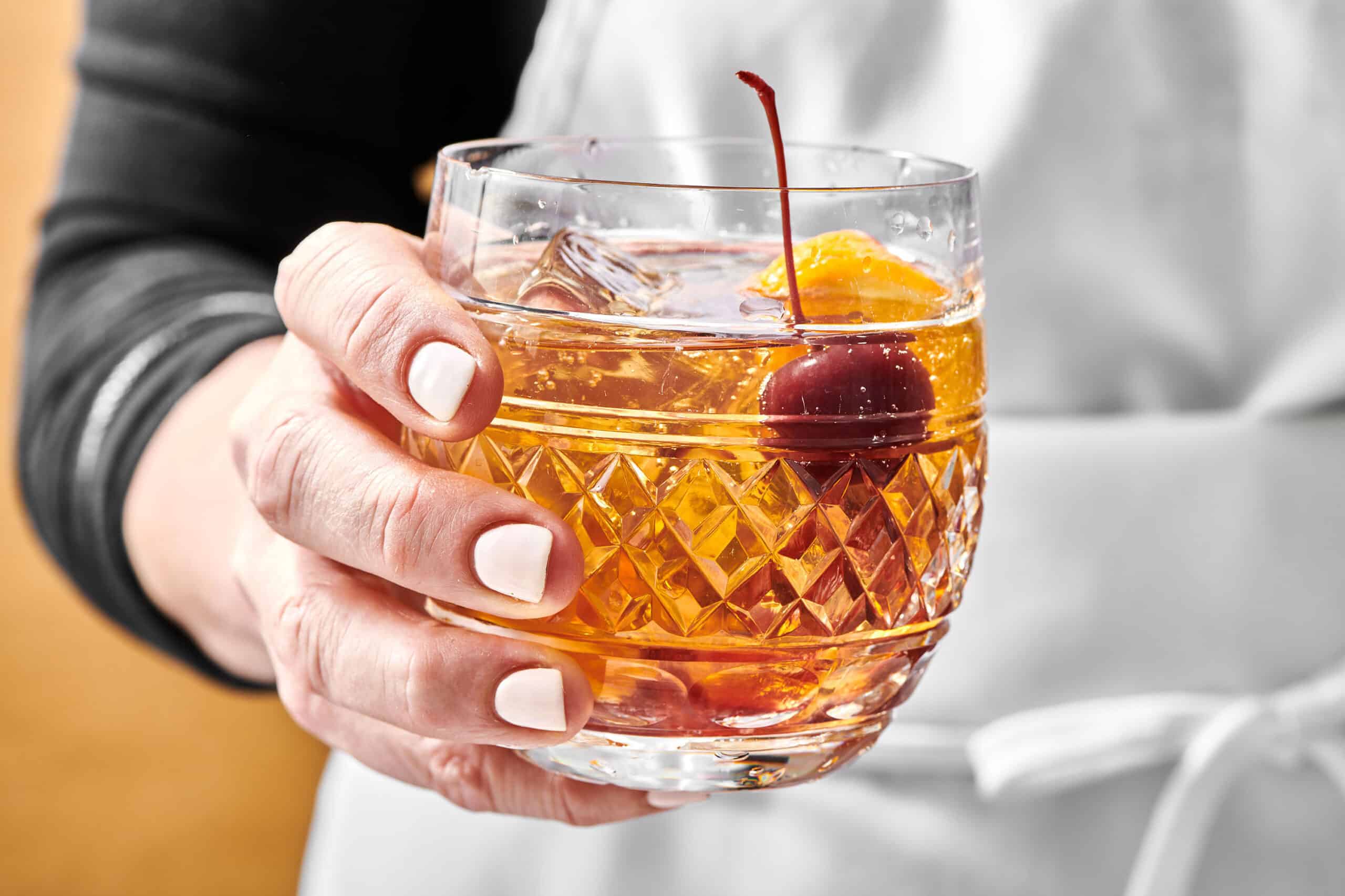 Woman holding an Old Fashioned in a rocks glass.