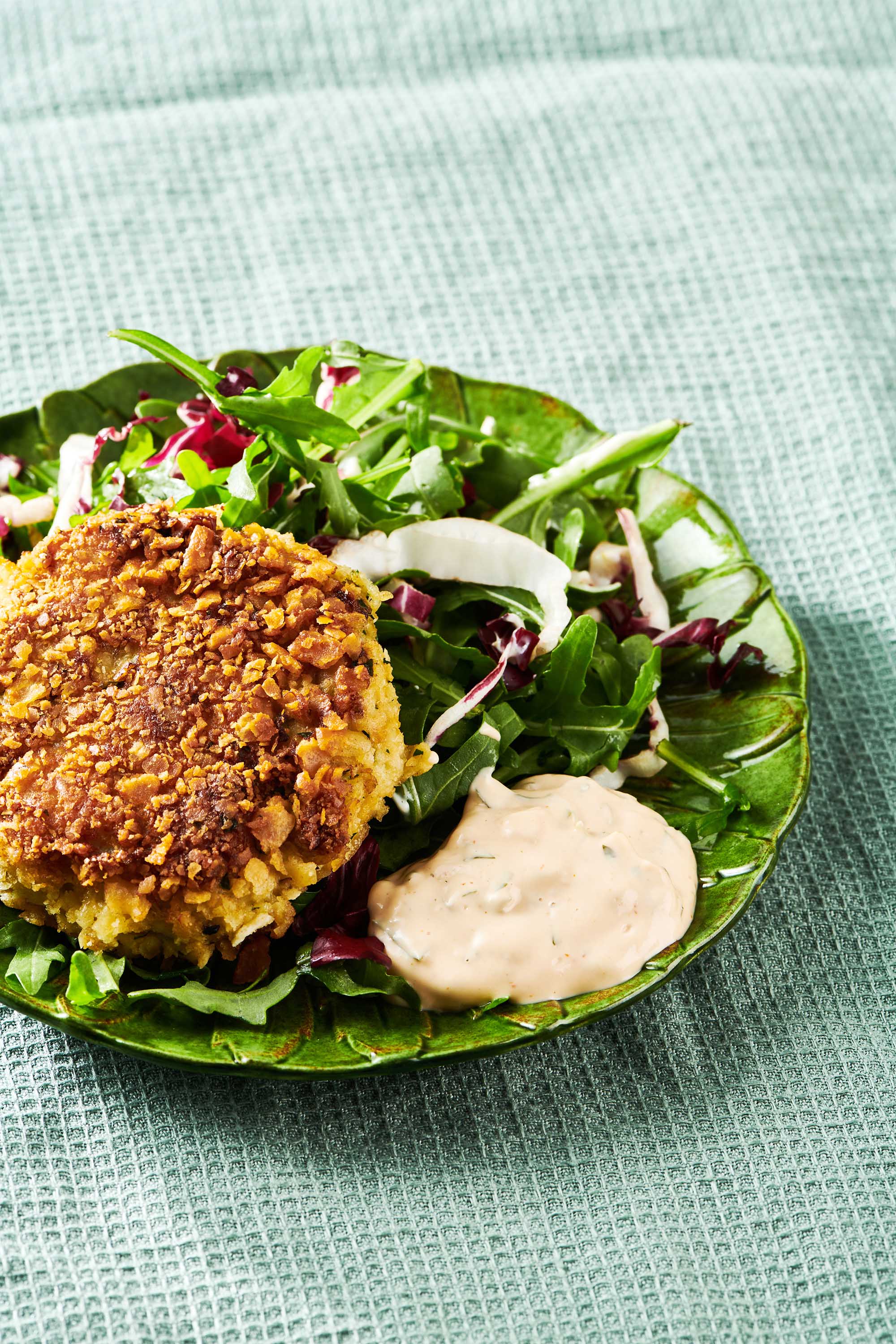 Crab Cake with Salad and Remoulade Sauce on a green plae.