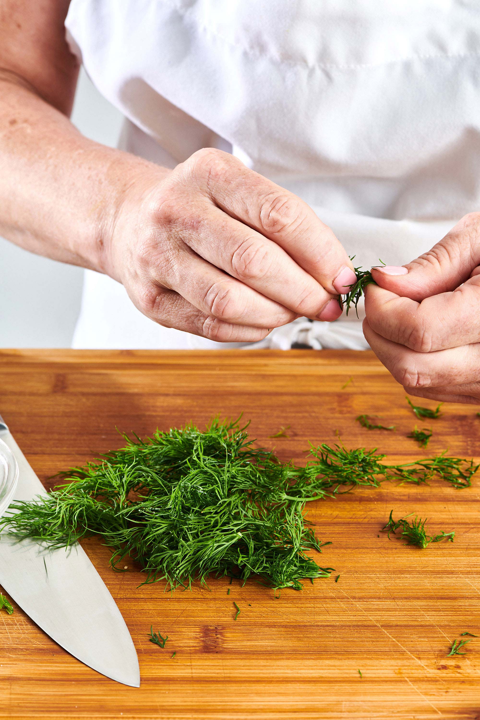 Preparing fresh dill on cutting board.