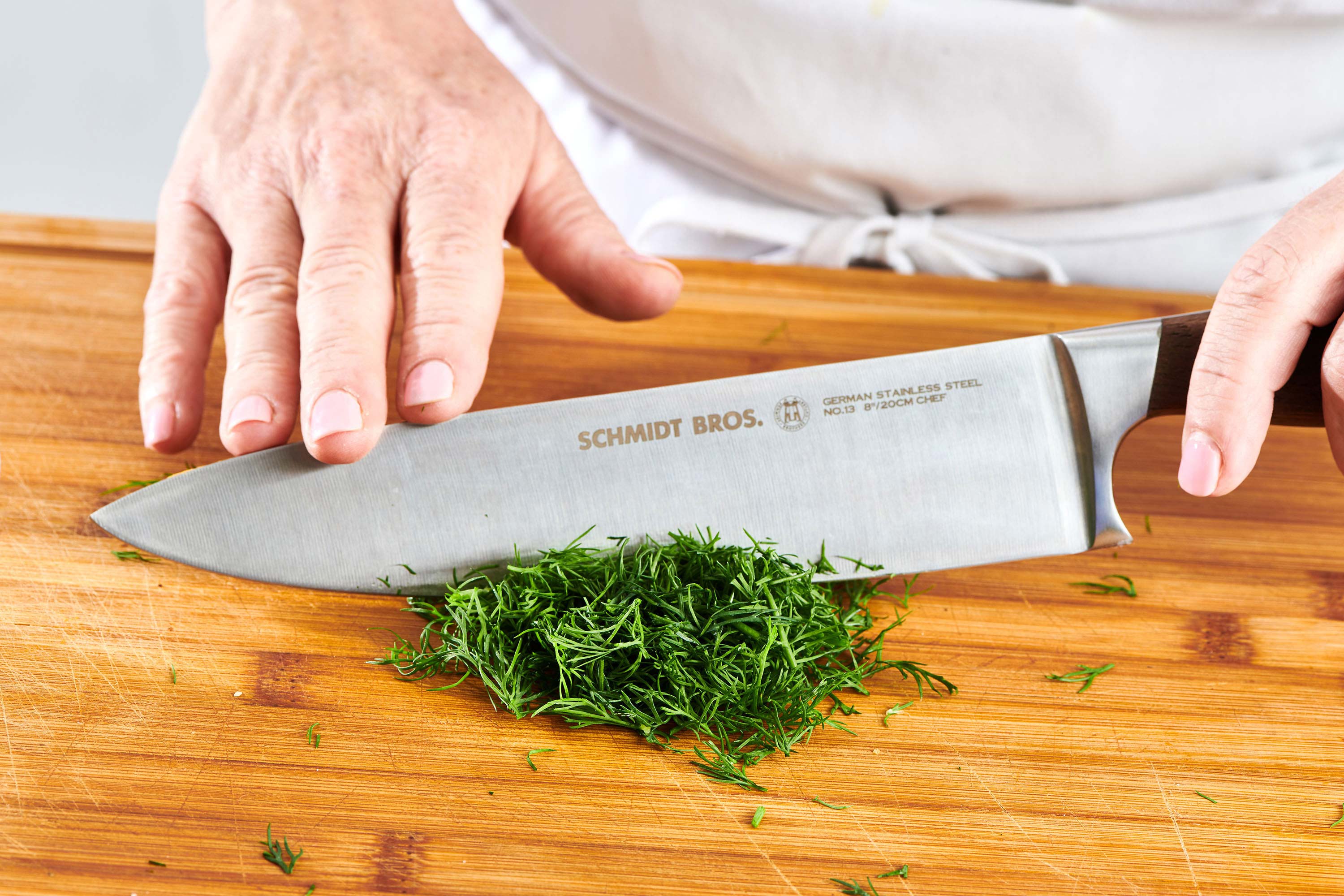 Chopping fresh dill on cutting board.