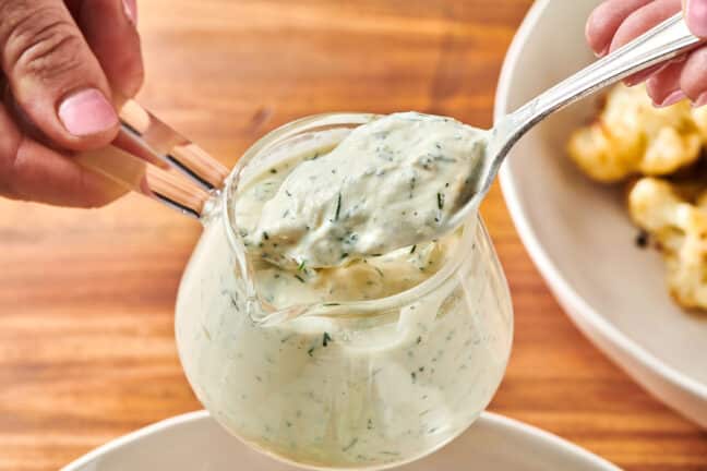 Spooning freshly made dill sauce from jar