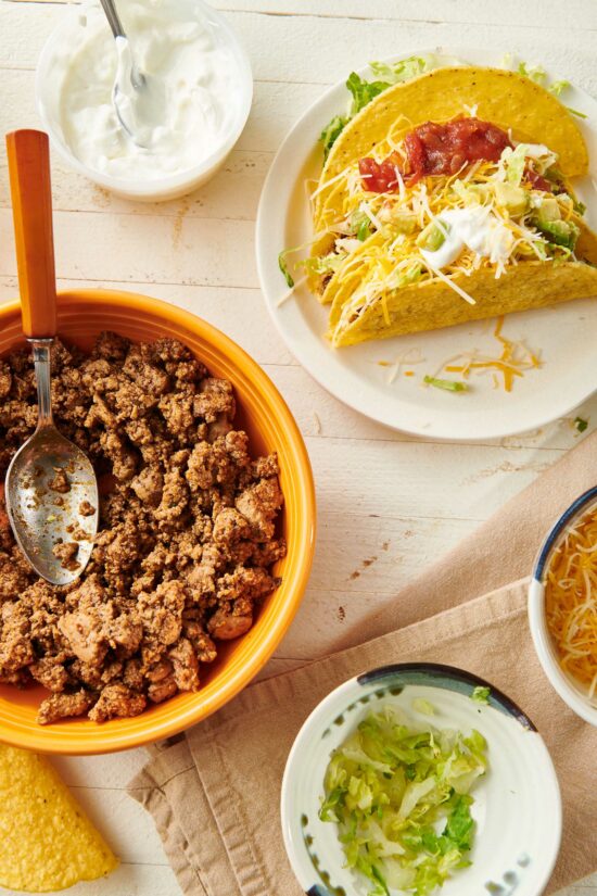 Plate of Ground Turkey Tacos on a table with bowls of taco ingredients.