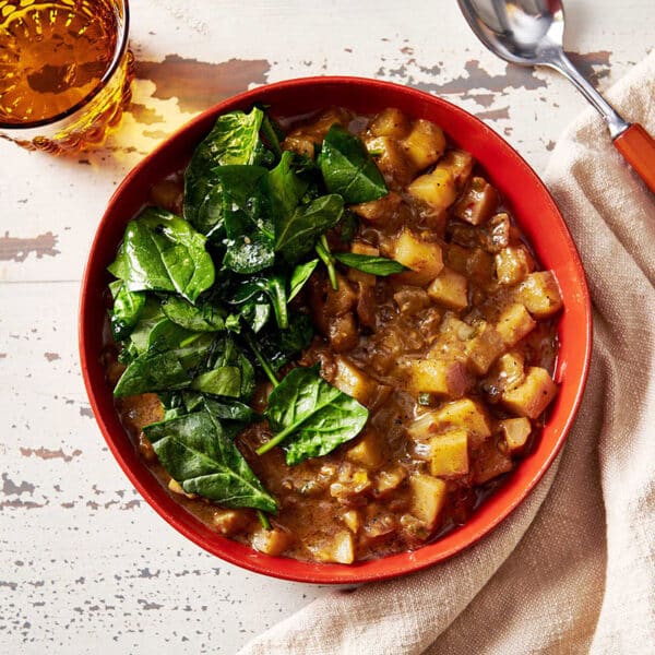 Potato Curry in red bowl on table.