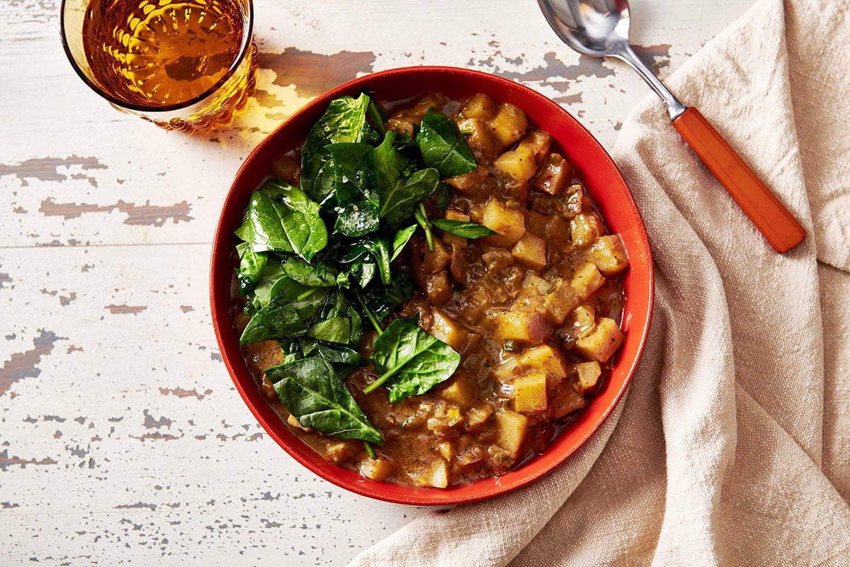 Potato Curry in red bowl on table.