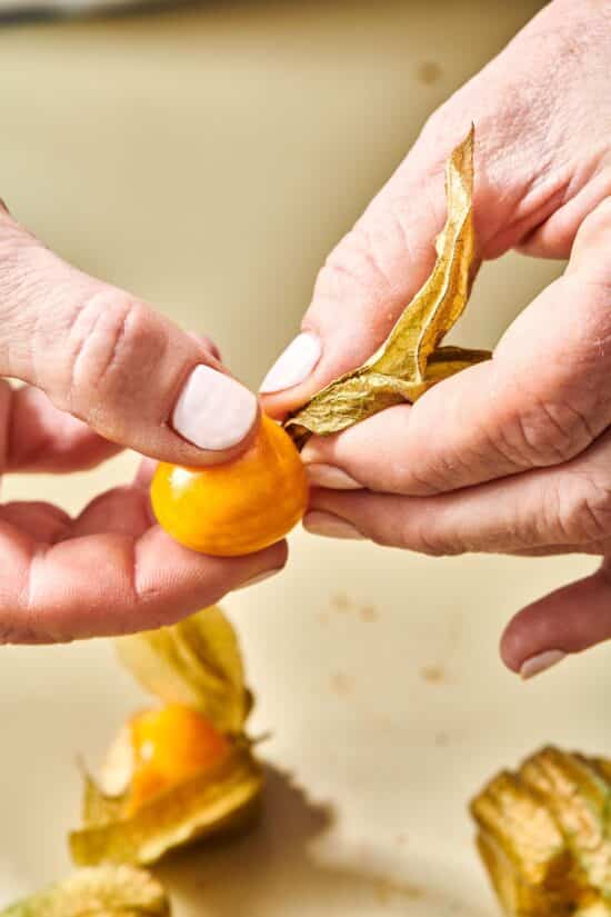 Woman removing the husk from a golden berry.