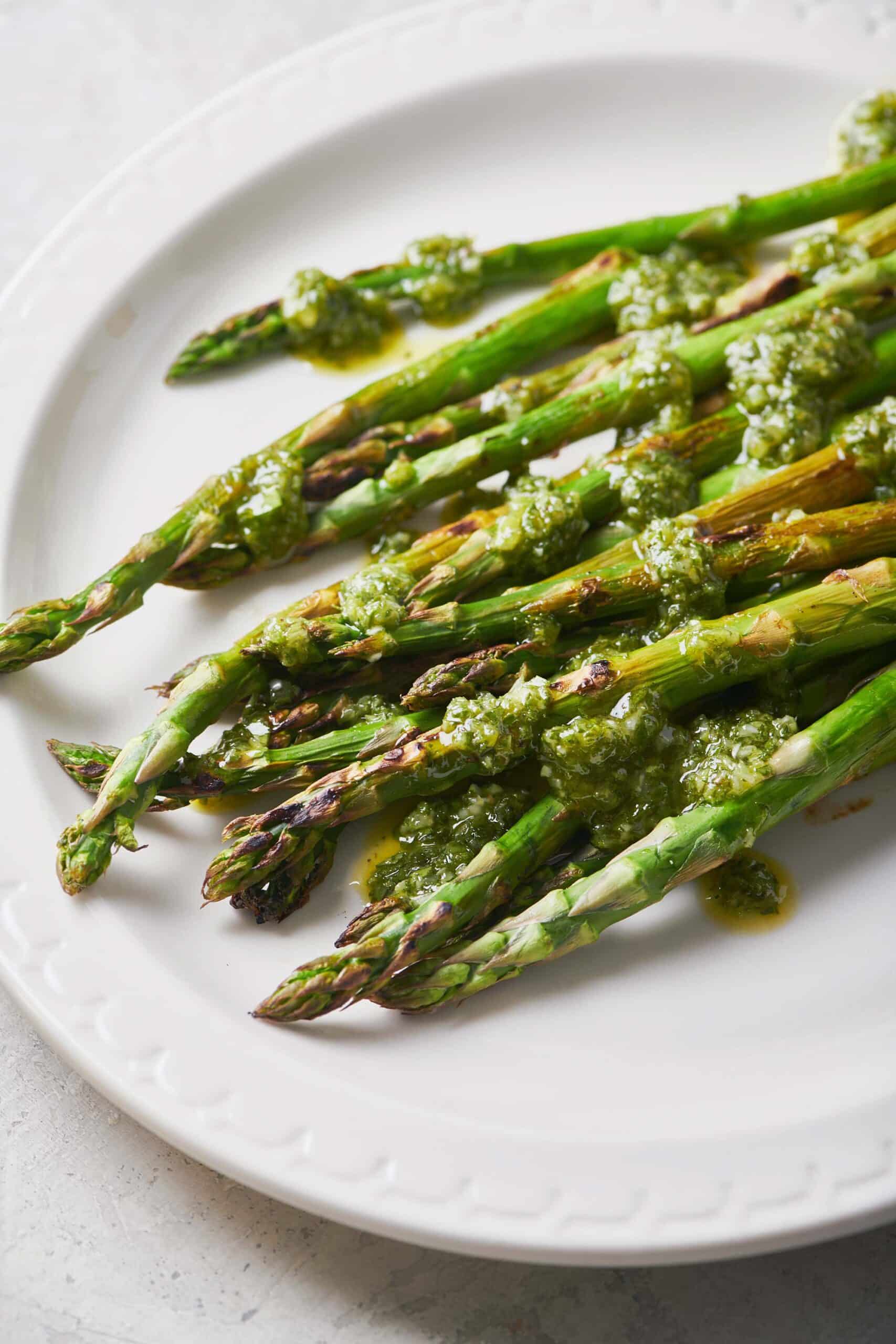 White plate of Asparagus with Scallion Chimichurri Sauce.
