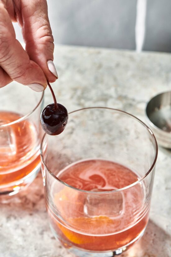 Woman placing a cherry into a small glass.