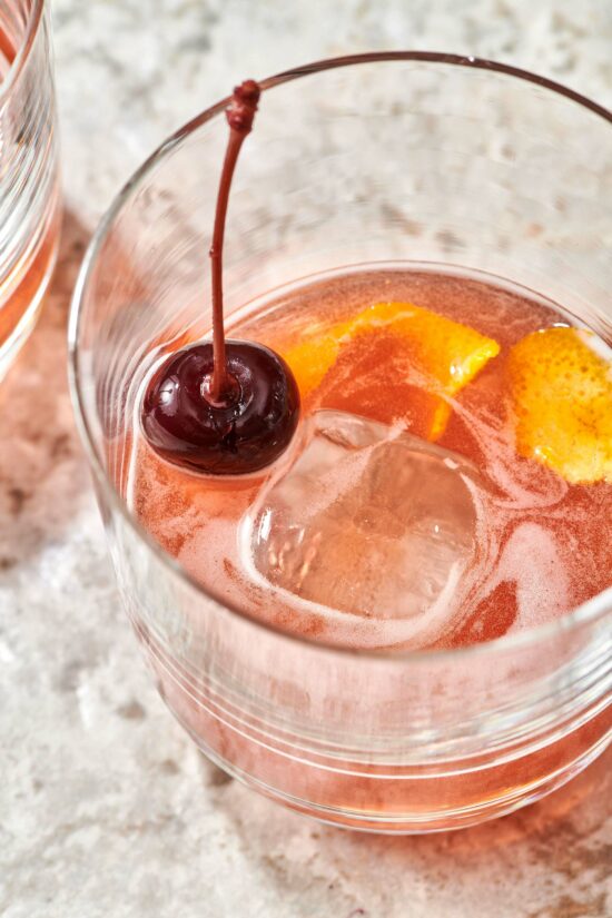 Cherry, orange peel, and ice in a Boulevardier Cocktail.
