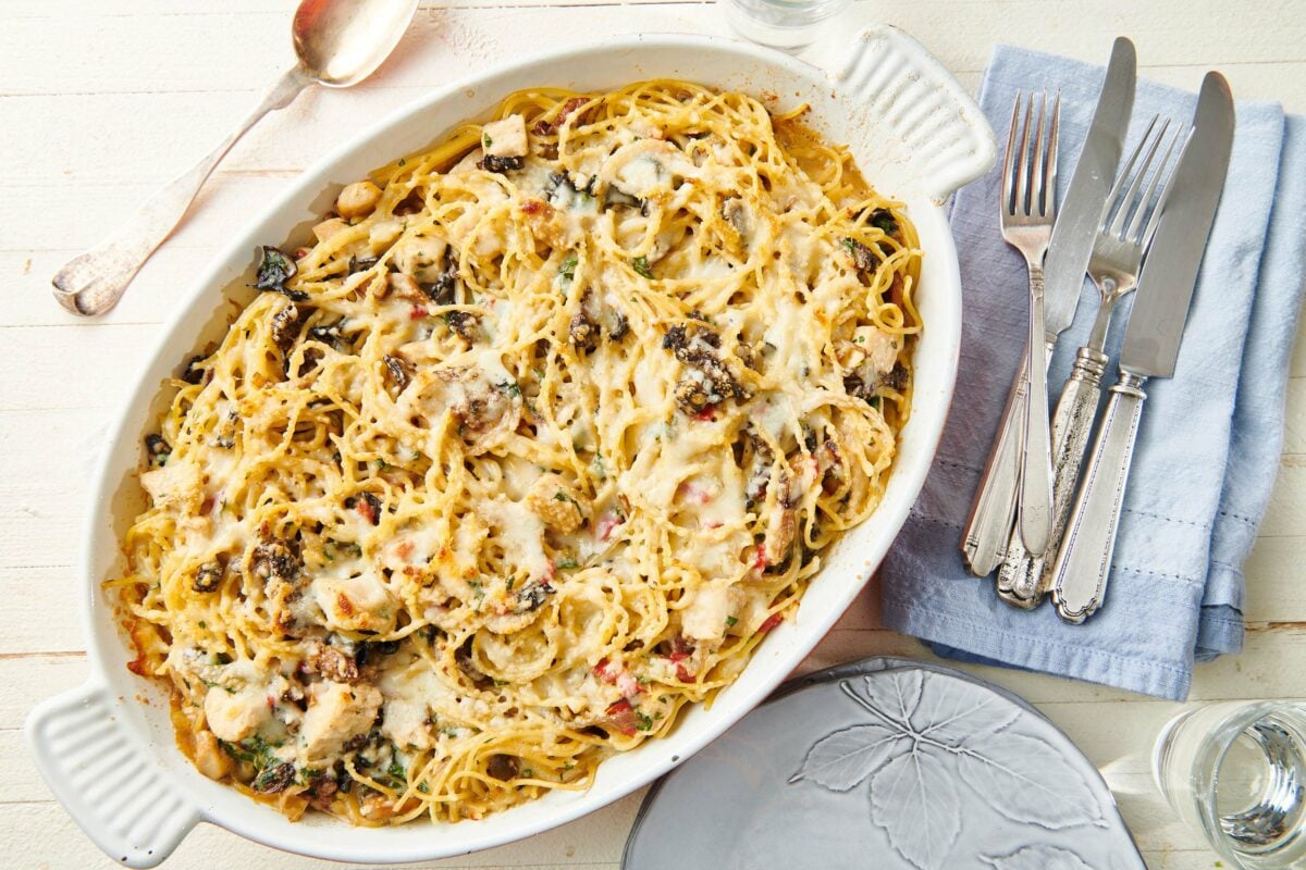 Baking dish of Chicken Tetrazzini on a table with utensils.