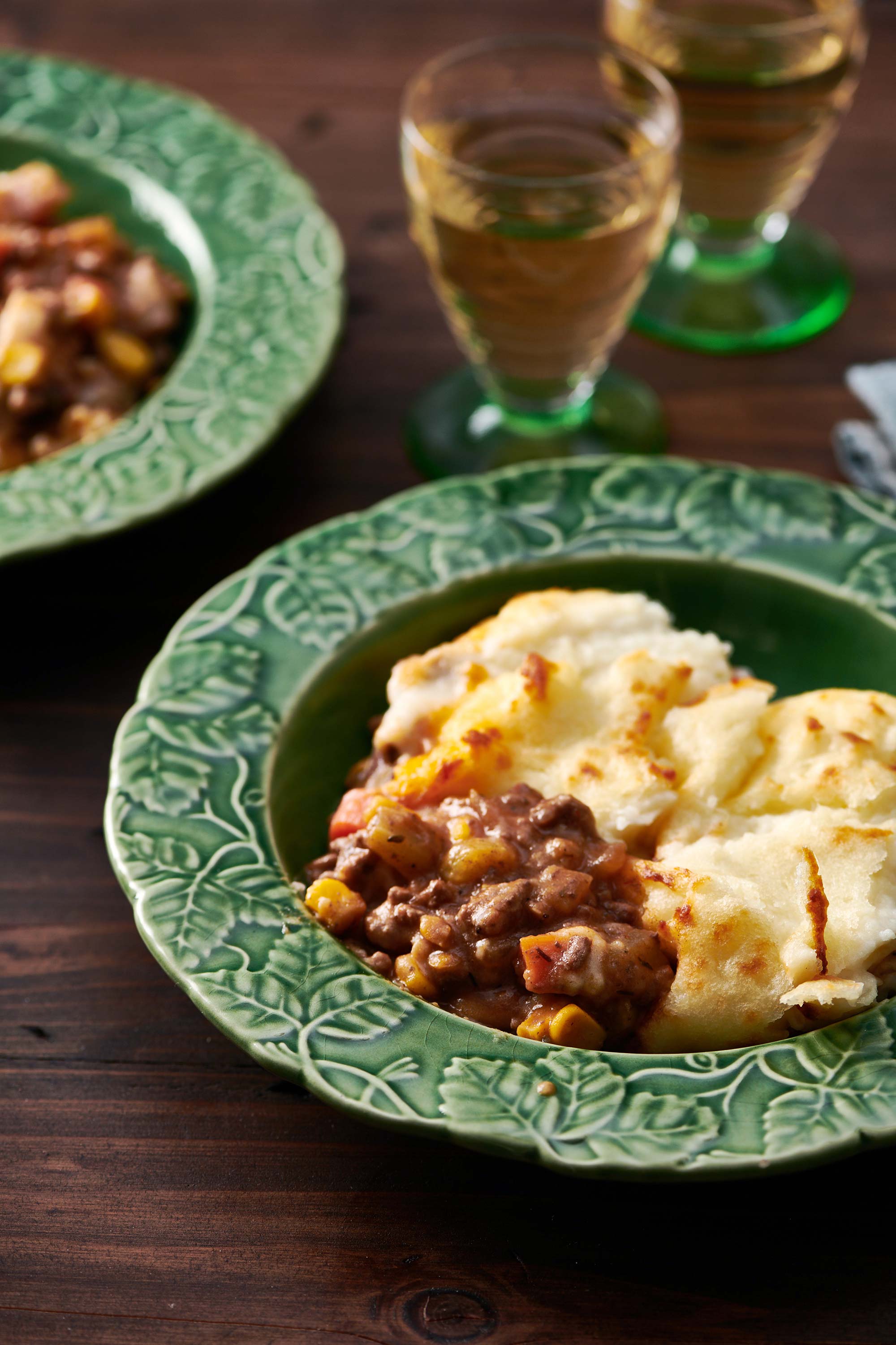 Two bowls of Cottage Pie on a wooden table.