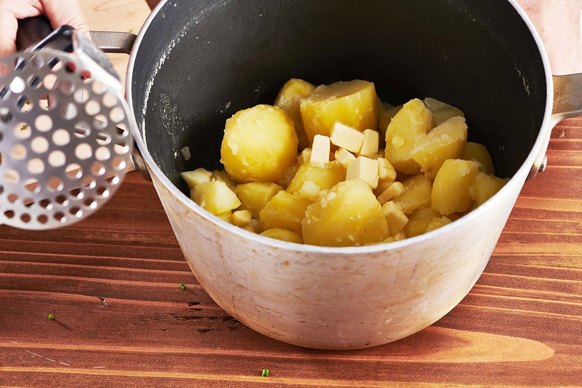 Boiled and drained potatoes in pot on table.