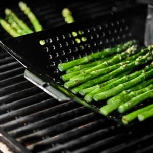 Asparagus in a grill basket on a grill.
