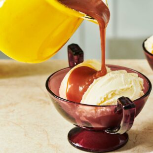 Yellow pitcher of Caramel Sauce pouring over ice cream.