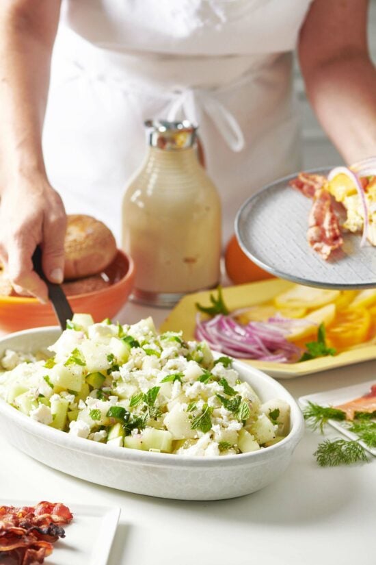 Woman filling her plate with breakfast foods.