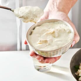 Woman holding a small bowl and a spoon of horseradish sauce.