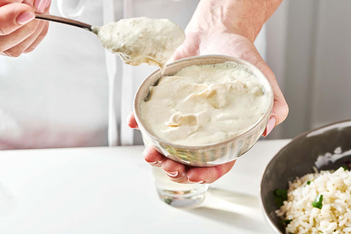 Woman holding a small bowl and a spoon of horseradish sauce.