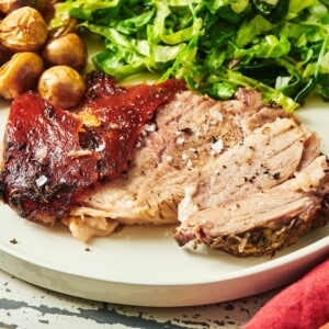 Porchetta on a plate with salad and potatoes.