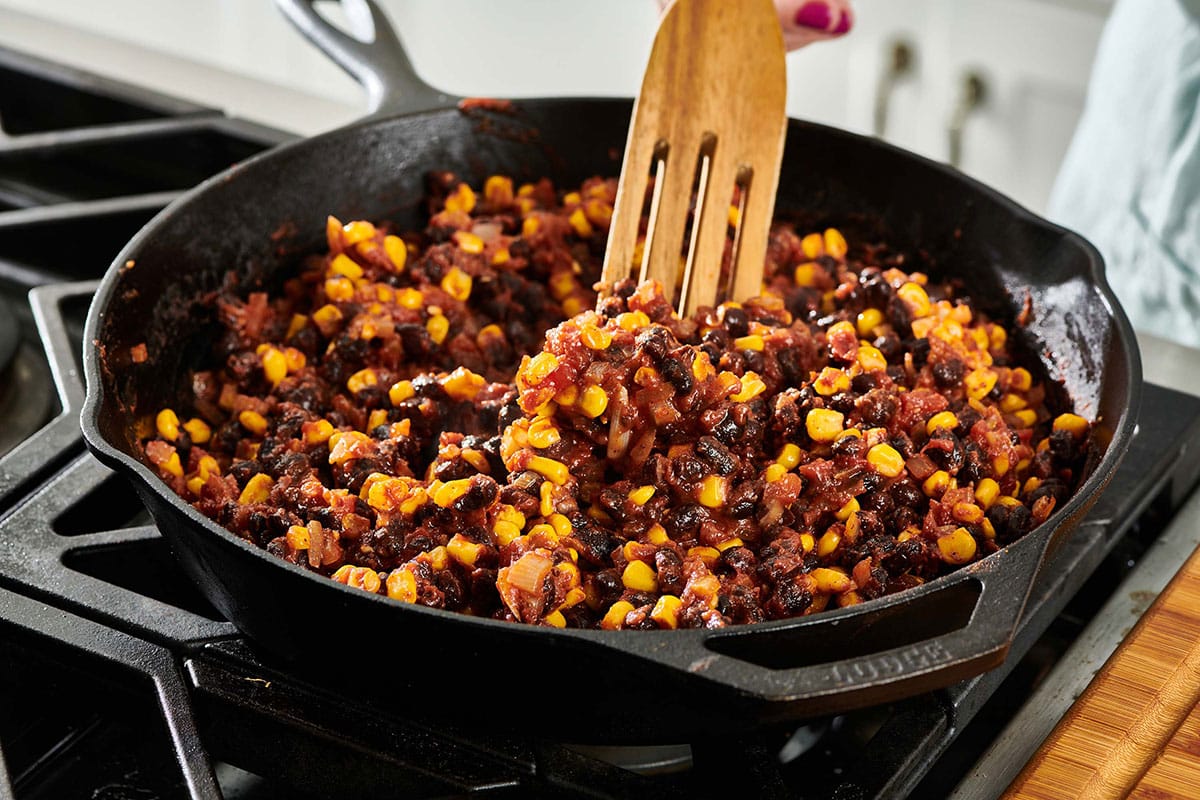 Wooden spatula stirring Vegetarian Mexican Lasagna filling.