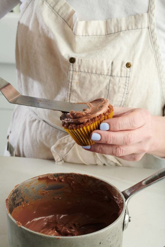 Woman spreading frosting onto a Carrot Cake Cupcake.