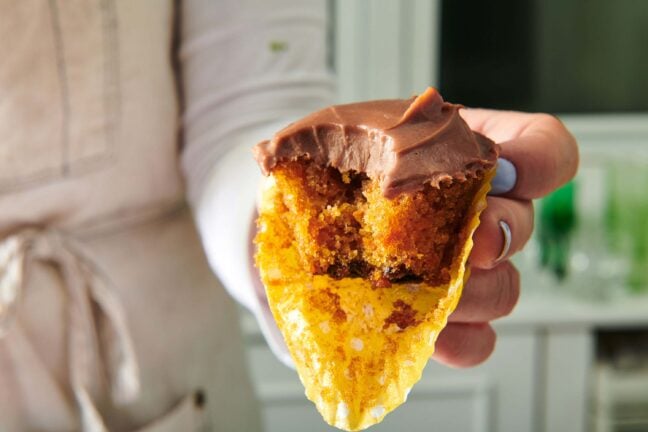 Woman holding a Carrot Cake Cupcake missing a bite.