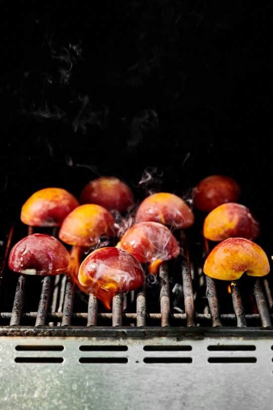 Halved peaches cut-side-down on a grill.