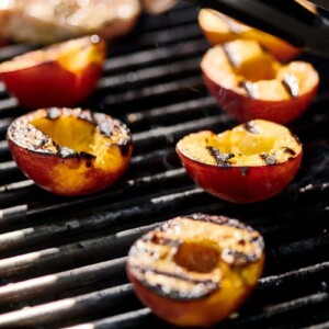 Peach halves with grill marks on a grill.