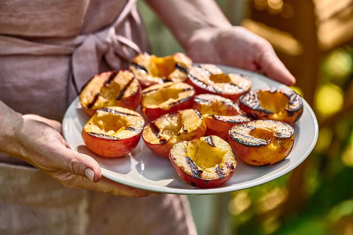 Woman carrying a plate of Grilled Peaches.