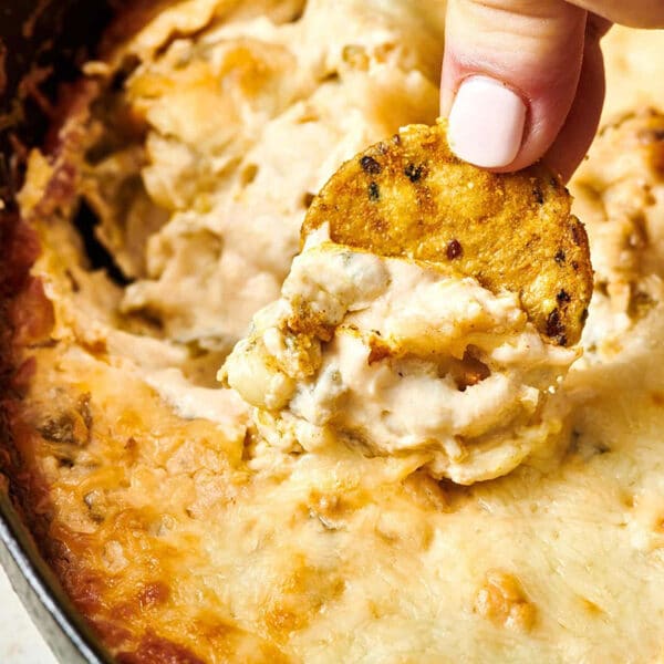 Woman dipping tortilla chip into pan of Hatch chile dip.