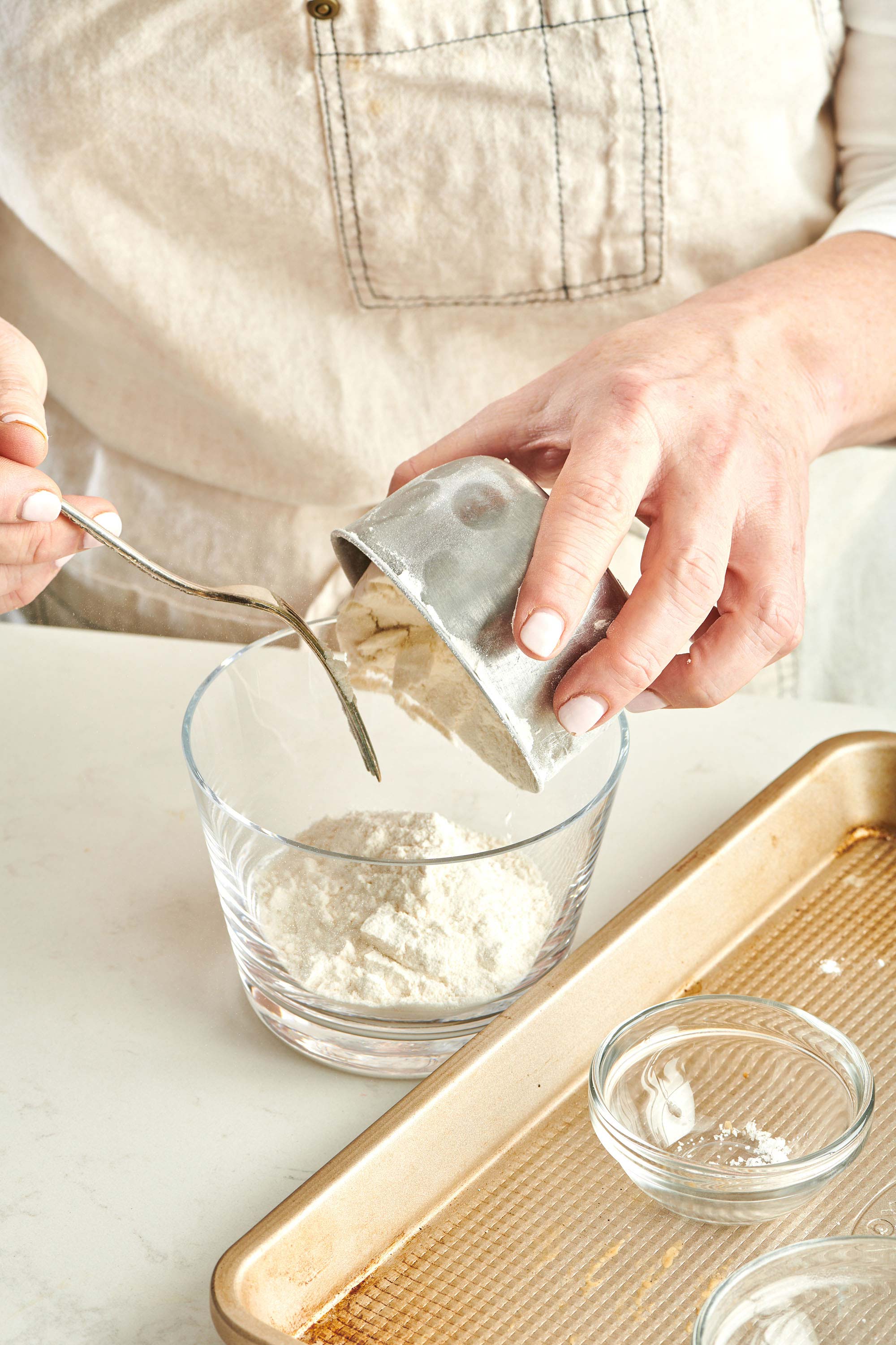 Woman pouring flour into glass jar.