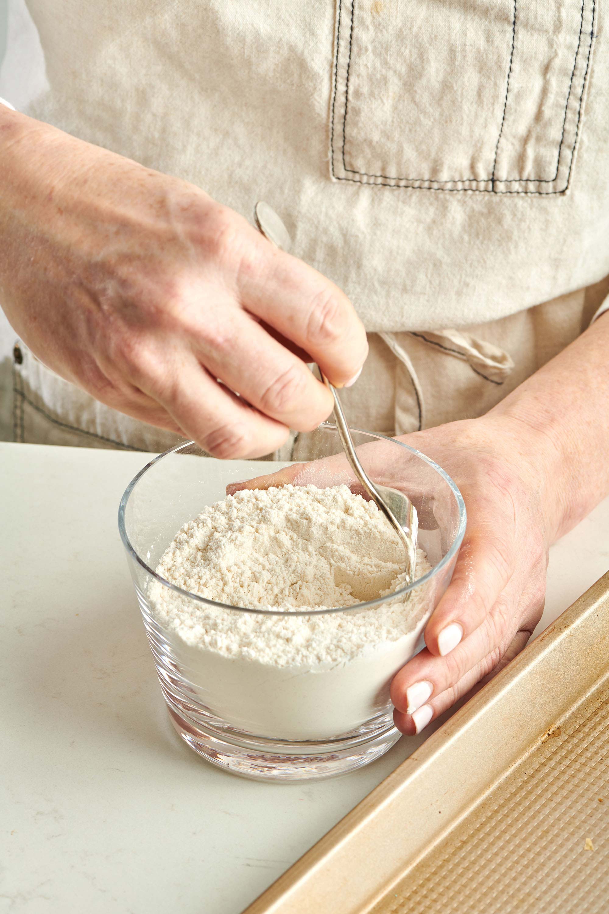 Woman stirring a small bowl of self-rising flour with a fork.