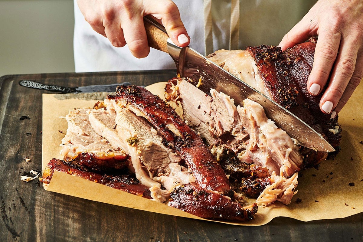 Woman slicing porchetta with large knife