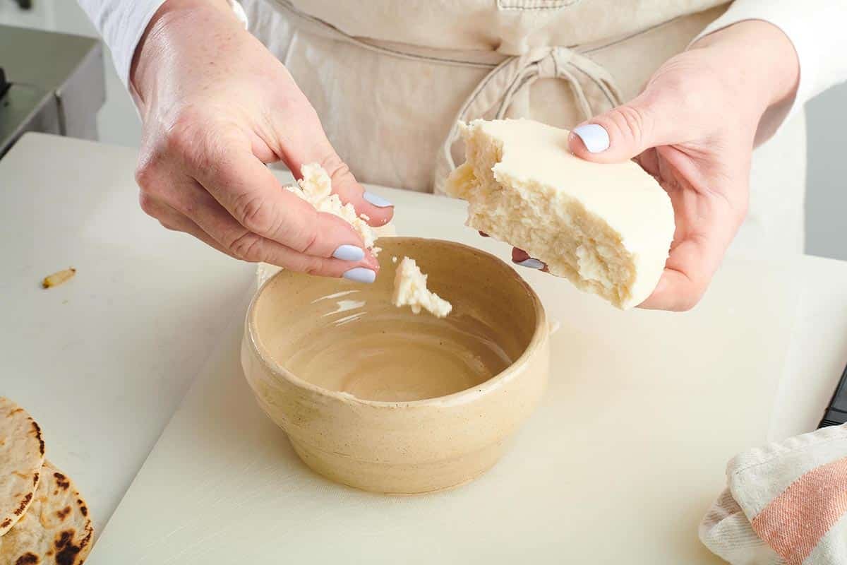 Woman crumbling queso fresco into a bowl.