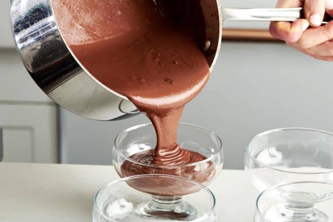 Chocolate Pudding pouring from a pot into large serving cups.
