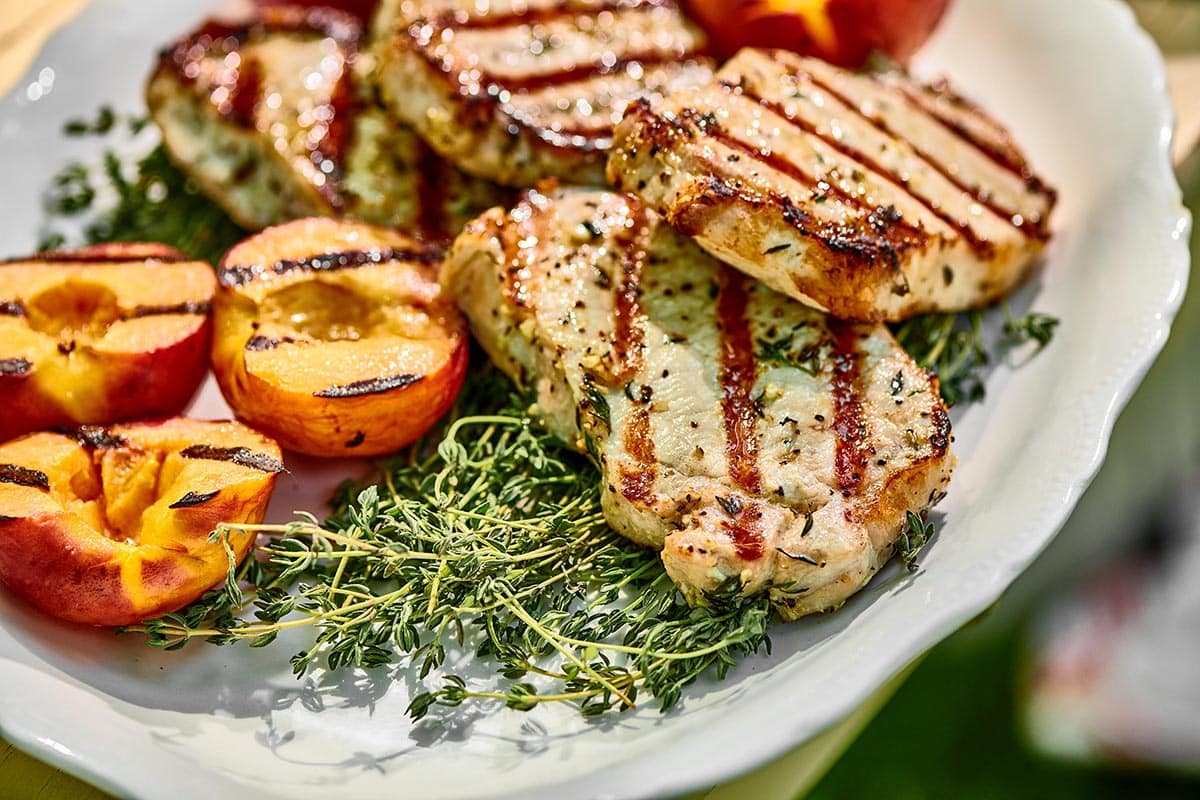Grilled Pork Chops with Peaches on plate with fresh thyme.