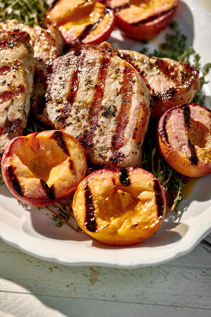 Grilled Pork Chops and Peaches piled high on white plate.