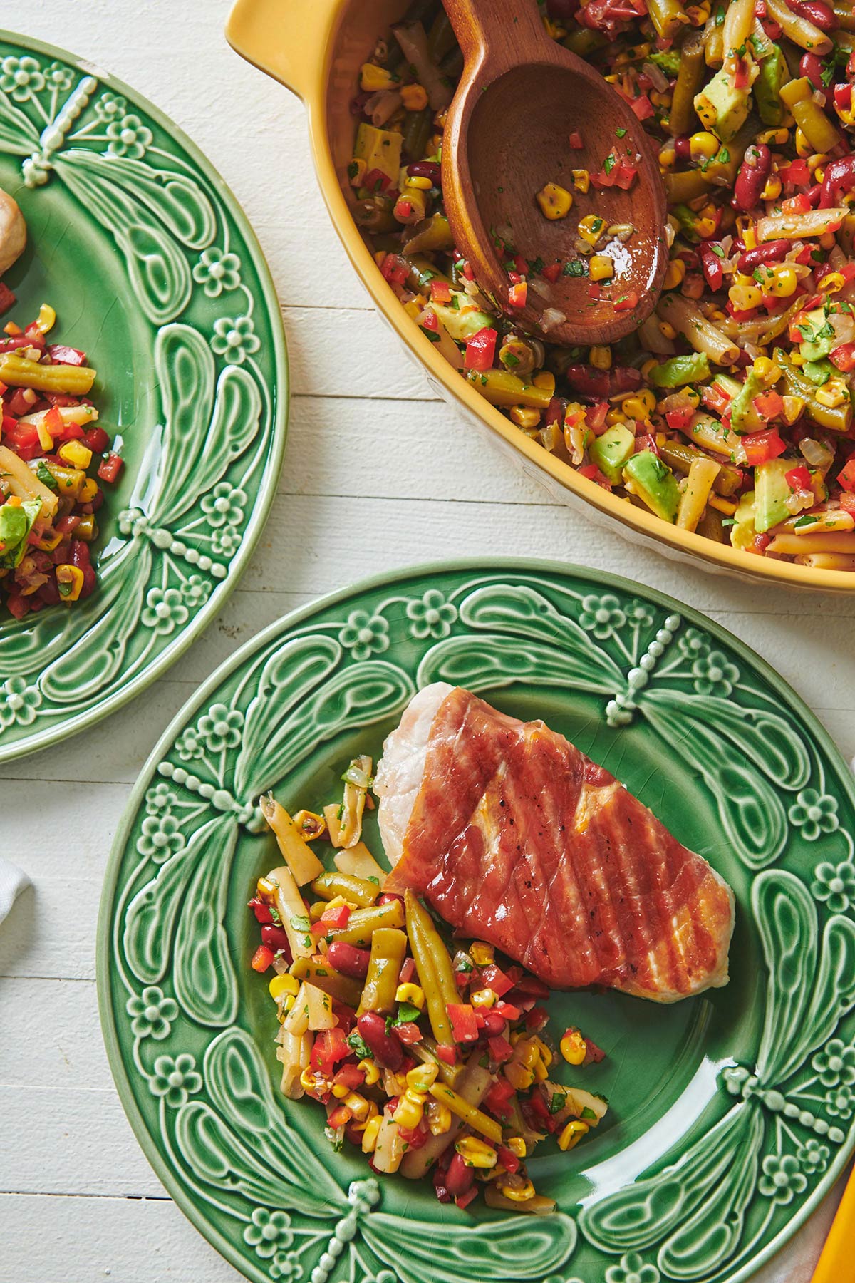 Grilled Prosciutto Wrapped Pork Chops on plates with vegetables.