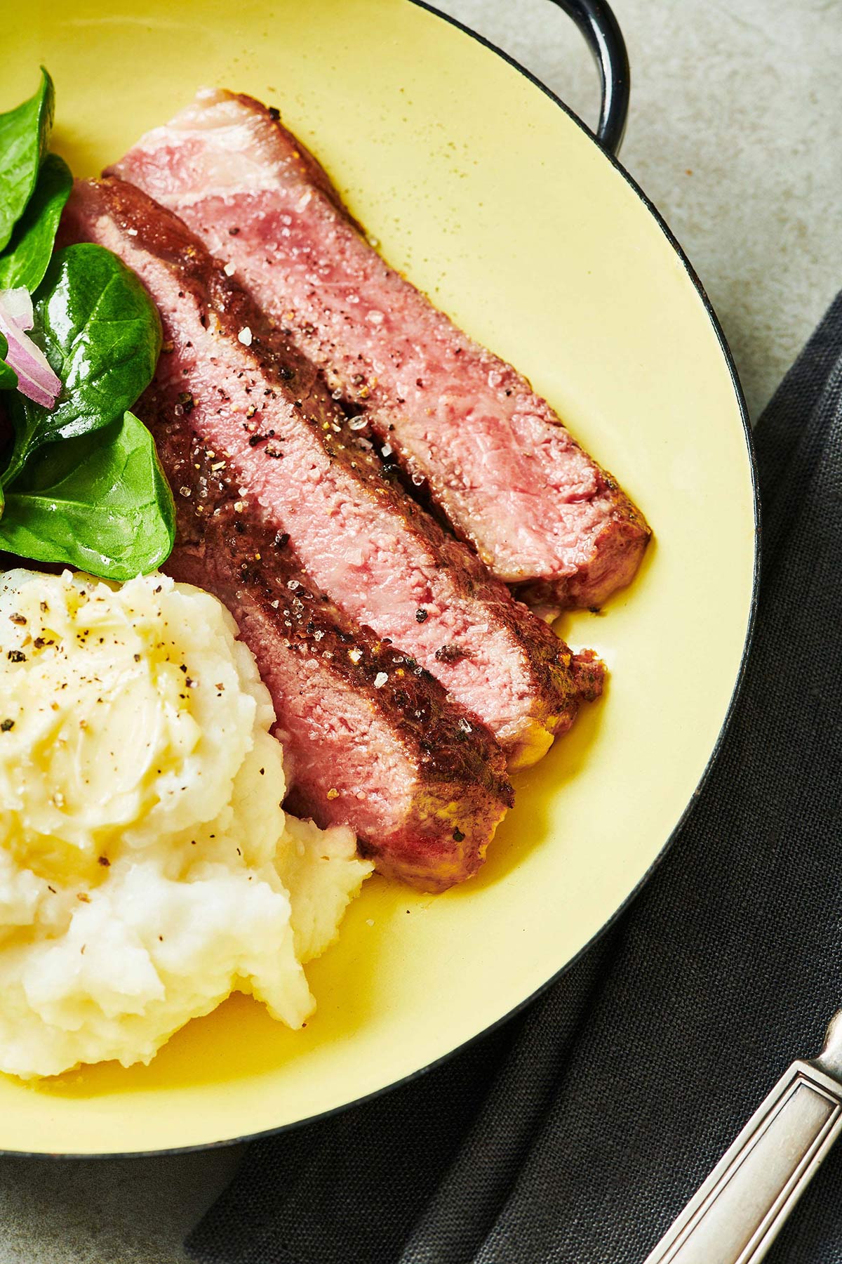Ribeye steak on plate with side dishes.