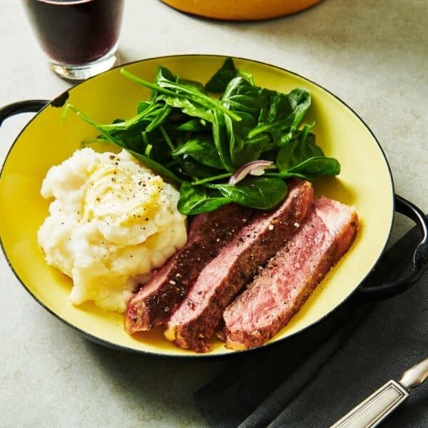 Pan-seared ribeye on plate with mashed potatoes and salad.