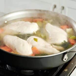 Chicken floating in a steaming pan.
