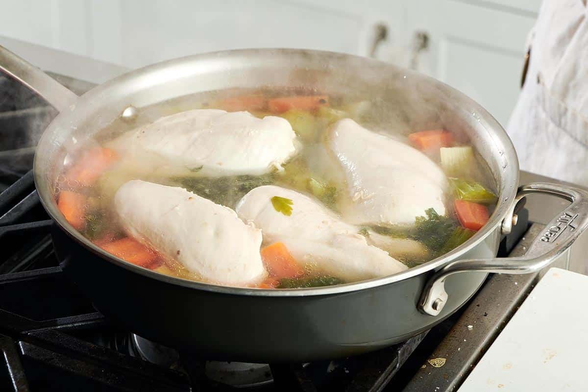 Chicken floating in a steaming pan.