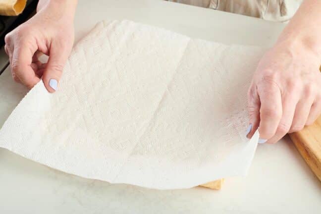 Woman putting paper towel on a cutting board.